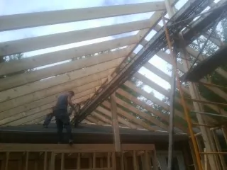 Rafters going up over a new addition with a worker on the wall in Appleton