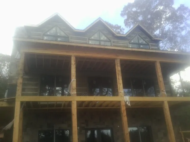 Dormers and porch framing on a large log home under construction — Roof Coating work by our crew in Appleton